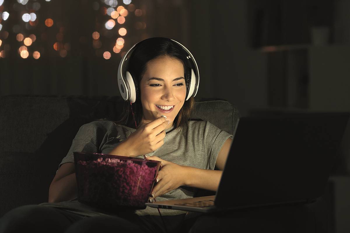 Frau mit großem Kopfhörer bei Nacht vor einem Computer